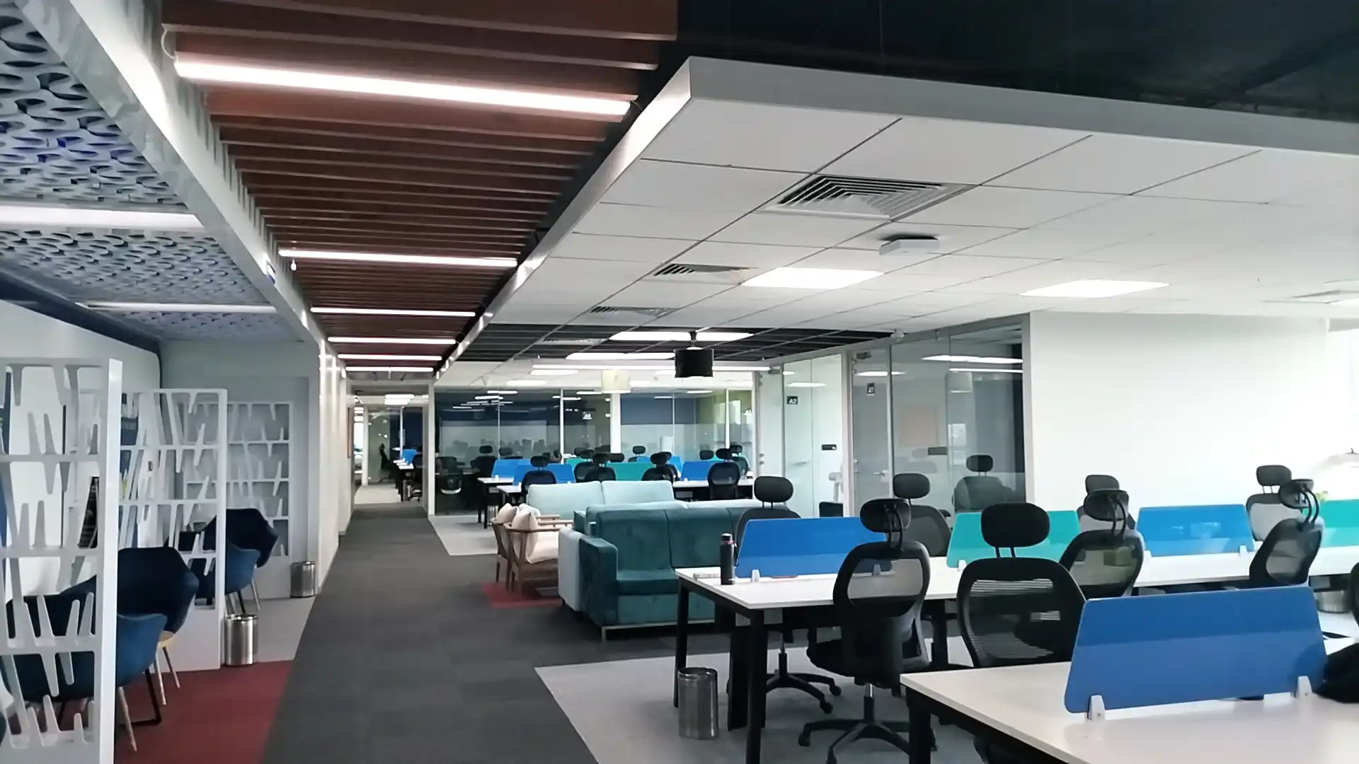 Modern open office with desks, chairs, glass meeting rooms, and lounge seating